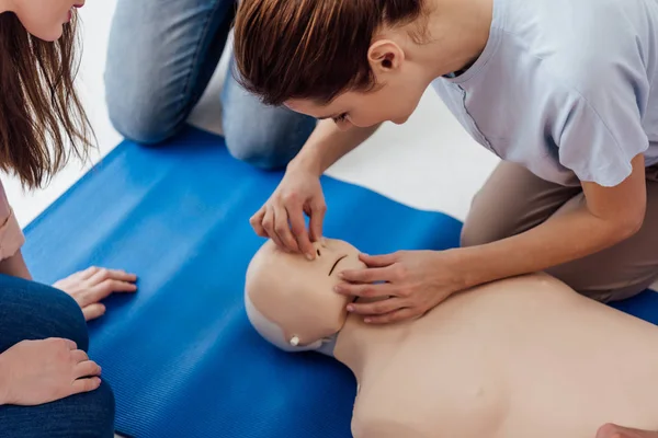 Ausgeschnittene Ansicht einer Frau, die während eines Erste-Hilfe-Trainings CPR-Technik an einem Dummy übt — Stockfoto