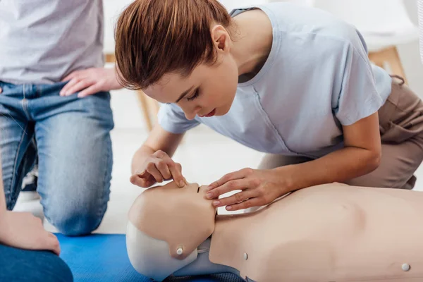 Woman practicing cpr technique on dummy during first aid training — Stock Photo