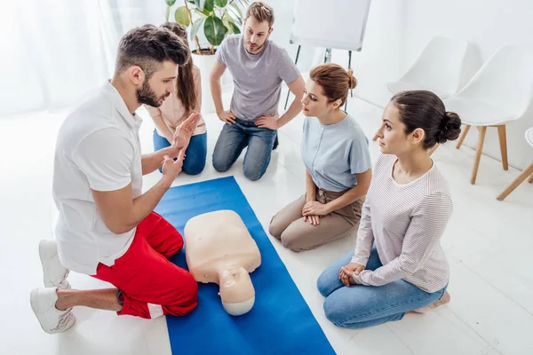 Bonito instrutor gesto durante o treinamento de primeiros socorros com grupo de pessoas — Fotografia de Stock