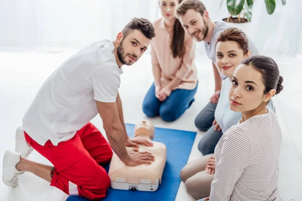 Group of people with instructor looking at camera during first aid training — Stock Photo