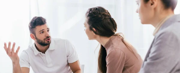 Panoramic shot of man gesturing and talking during group therapy session — Stock Photo