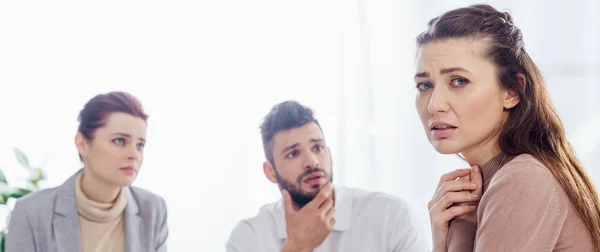 Panoramic shot of worried woman looking at camera during group therapy session — Stock Photo