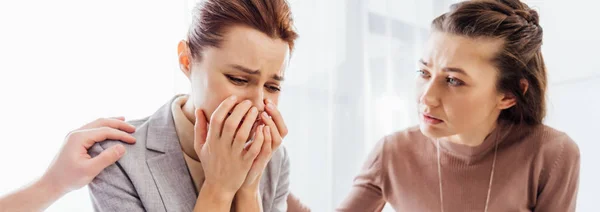 Панорамний знімок жінки, що втішає іншу плачучу жінку під час терапевтичної зустрічі — стокове фото