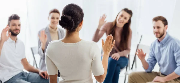 Panoramaaufnahme von Menschen, die auf Stühlen sitzen und während einer Sitzung der Selbsthilfegruppe die Hände heben — Stockfoto