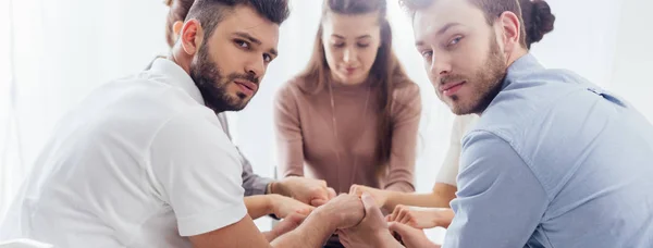 Panoramic shot of group of people sitting and stacking hands during therapy session — Stock Photo