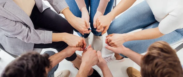 Prise de vue panoramique de personnes se tenant la main pendant une séance de thérapie de groupe — Photo de stock