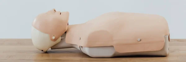 Panoramic shot of cpr dummy for first aid training on wooden table — Stock Photo