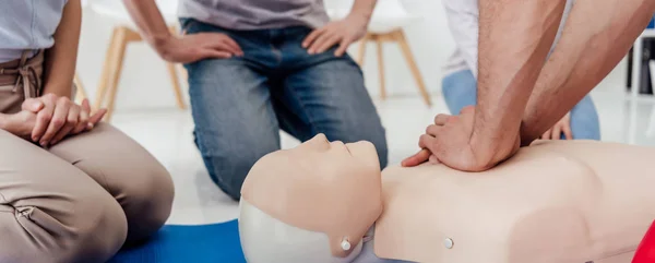 Vista recortada del hombre realizando compresión torácica en maniquí durante la clase de entrenamiento cpr - foto de stock