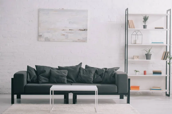 Чорний диван біля журнального столика і стійки в сучасній вітальні — Stock Photo