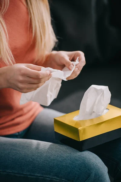 Abgeschnittene Ansicht einer Frau, die sich in Gewebe in der Nähe von Gewebekasten zu Hause hält — Stockfoto