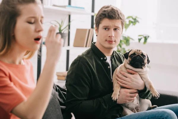 Вибірковий фокус людина тримає чарівні мопс і дивлячись на дівчину, алергія на собаку за допомогою інгалятор — стокове фото