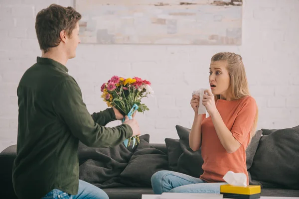 Homme tenant des fleurs près de femme choquée avec allergie au pollen — Photo de stock