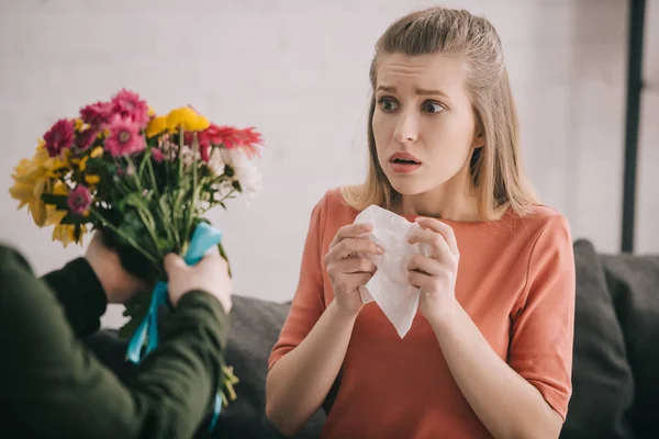 Vue recadrée d'un homme tenant des fleurs près d'une femme choquée allergique au pollen — Photo de stock