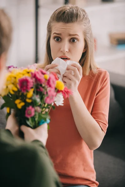 Cropped view of man holding flowers near shocked blonde girl with pollen allergy — Stock Photo