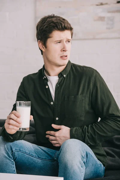 Красивый расстроенный мужчина со стаканом молока в желудке — стоковое фото