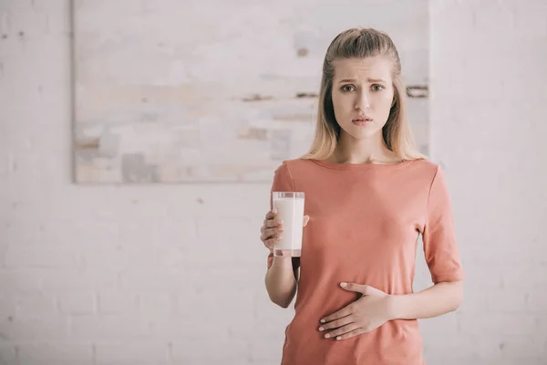 Mujer con intolerancia a la lactosa sosteniendo un vaso de leche - foto de stock
