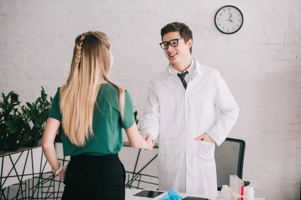 Rückansicht einer Frau beim Händeschütteln mit Arzt in Brille und weißem Mantel — Stockfoto