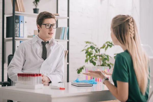 Foyer sélectif médecin dans des lunettes et manteau blanc parler avec patient blonde — Photo de stock