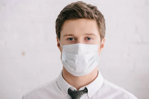 Mann in Anzug und medizinischer Maske blickt in Kamera — Stockfoto