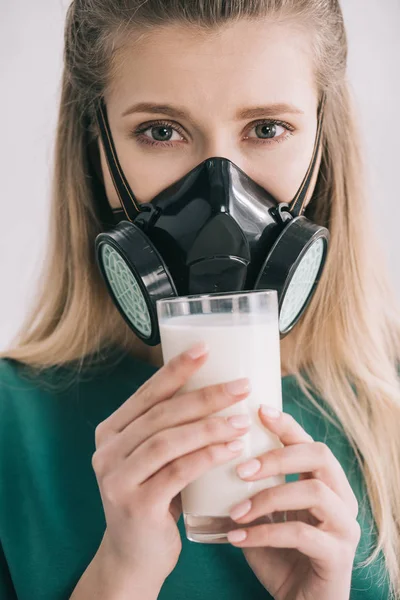 Primer plano de mujer rubia en máscara respiratoria sosteniendo vaso de leche - foto de stock