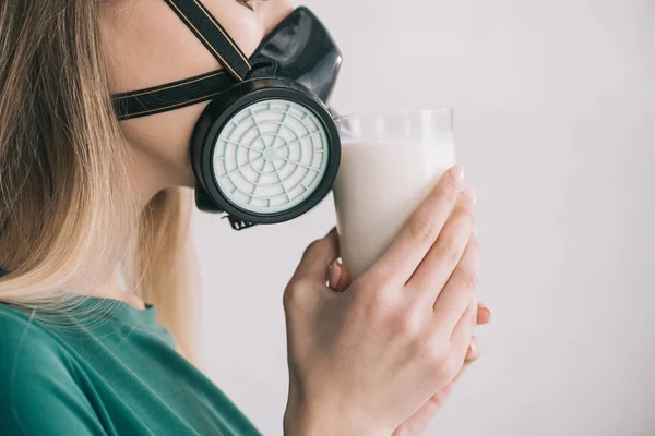 Vue recadrée de la femme blonde dans un masque respiratoire sentant le lait tout en tenant le verre — Photo de stock