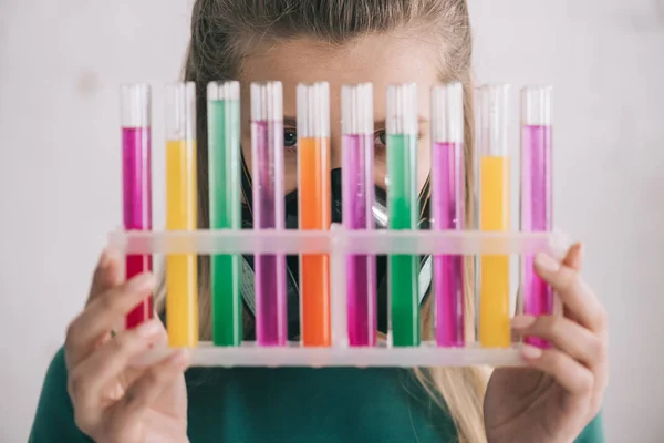 Woman holding glass and colorful test tubes — Stock Photo