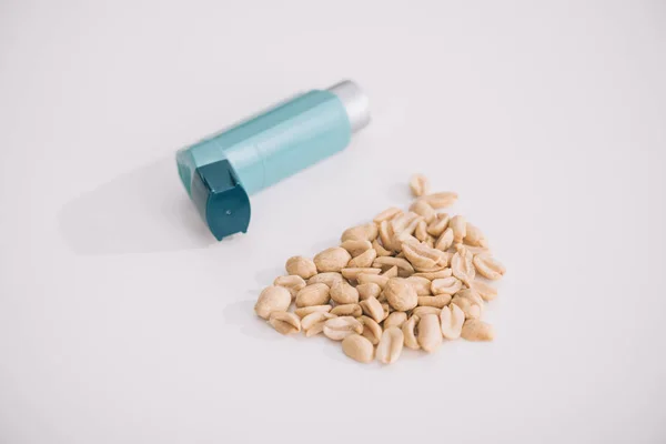 Inalador azul perto de amendoins nutritivos saborosos em cinza — Fotografia de Stock