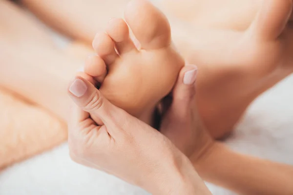 Vista cortada de massagista fazendo massagem nos pés para mulher adulta no spa — Fotografia de Stock