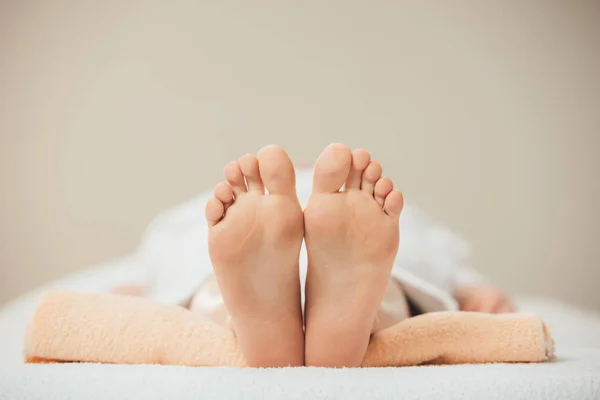 Селективное внимание взрослой женщины, лежащей на бежевом полотенце в спа — стоковое фото