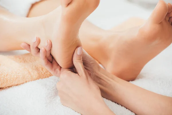 Vista recortada de masajista haciendo masaje de pies a mujer adulta en spa - foto de stock