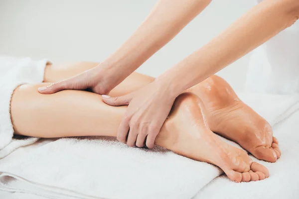 Vue partielle du masseur faisant massage des pieds à la femme adulte dans le spa — Photo de stock