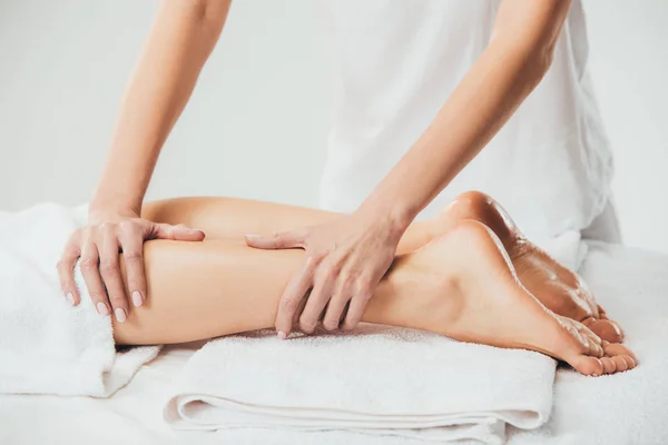 Vista parcial de masajista haciendo masaje de pies a mujer adulta en spa - foto de stock