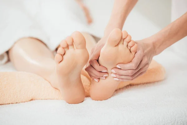Vista parziale del massaggiatore che fa massaggio ai piedi alla donna adulta nella spa — Foto stock