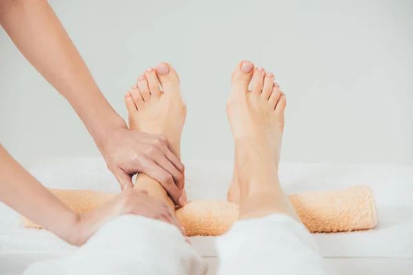 Vista parcial de masajista haciendo masaje de pies a mujer adulta en spa - foto de stock