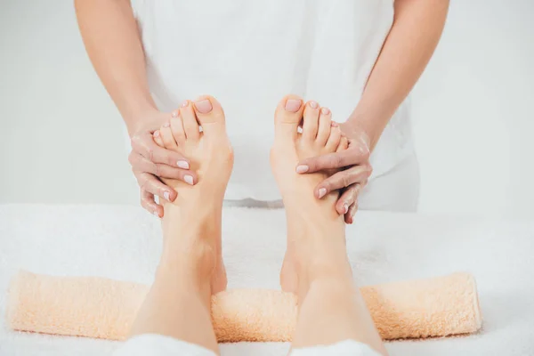 Vue partielle du masseur faisant massage des pieds à la femme adulte dans le spa — Photo de stock