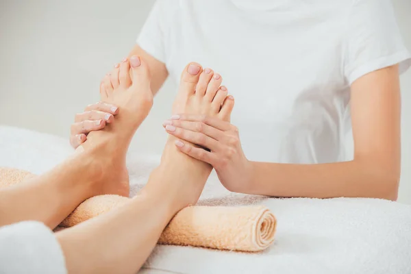 Частичный вид массажера, делающего массаж ног взрослой женщине в спа — стоковое фото