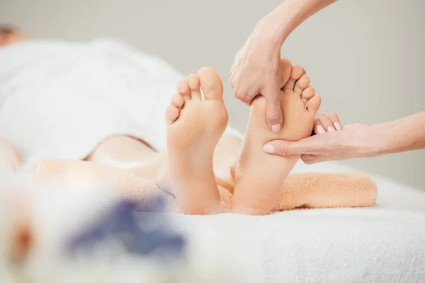 Foco seletivo de massagista fazendo massagem nos pés para mulher adulta no spa — Fotografia de Stock