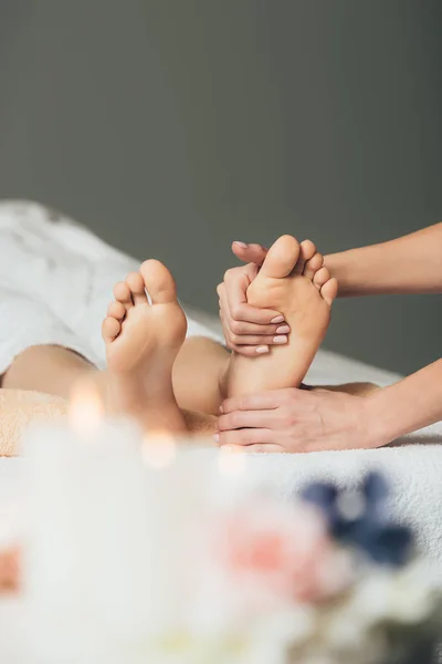 Vista parcial de masajista haciendo masaje de pies a mujer adulta en spa - foto de stock