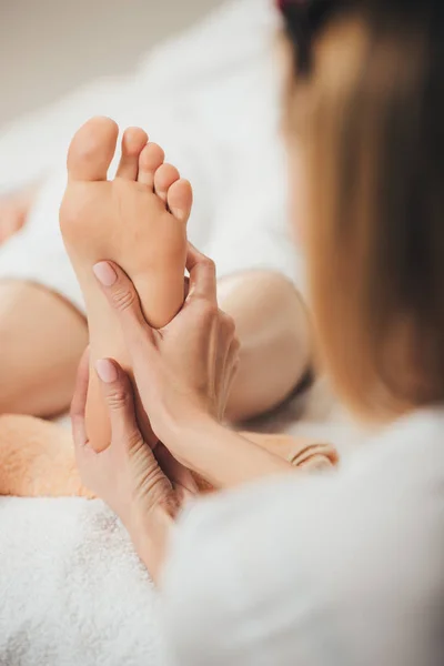 Vista cortada de massagista fazendo massagem nos pés para mulher adulta no spa — Fotografia de Stock