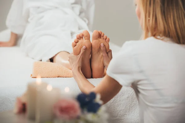 Vista recortada de masajista haciendo masaje de pies a mujer adulta en spa - foto de stock