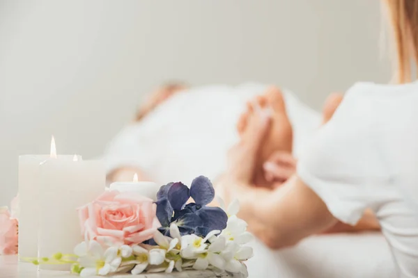 Vista recortada de masajista haciendo masaje de pies a mujer adulta en spa - foto de stock