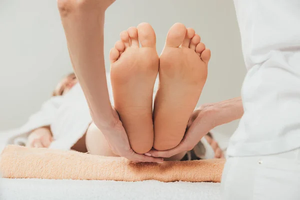 Vista recortada de masajista haciendo masaje de pies a mujer adulta en spa - foto de stock