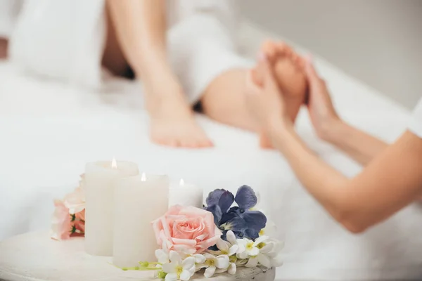 Messa a fuoco selettiva del massaggiatore facendo massaggio ai piedi alla donna adulta in spa — Foto stock