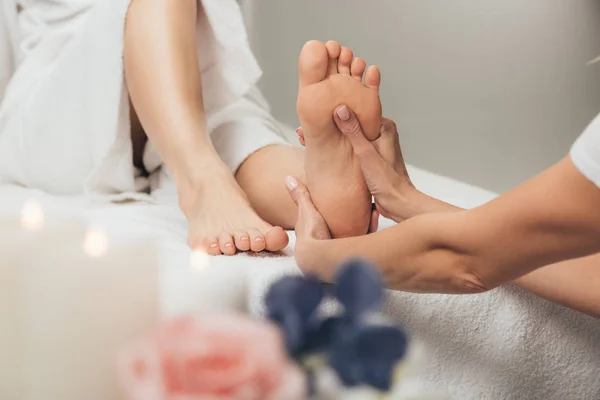 Vista recortada de masajista haciendo masaje de pies a mujer adulta en spa - foto de stock