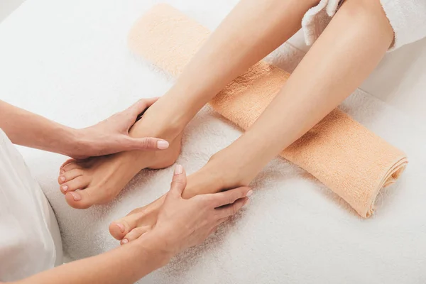 Cropped view of masseur doing foot massage to adult woman in spa — Stock Photo