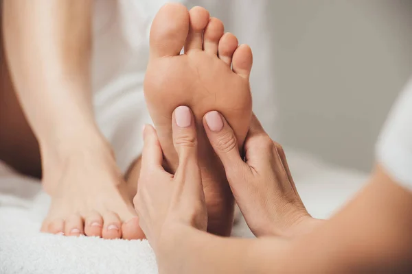 Vista recortada de masajista haciendo masaje de pies a mujer adulta en spa - foto de stock