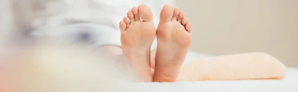 Panoramic shot of adult woman lying on beige towel in spa — Stock Photo