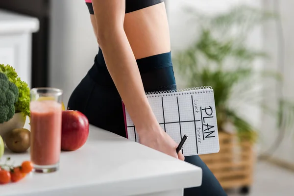 Vista cortada de mulher segurando notebook com plano de letras na cozinha — Fotografia de Stock