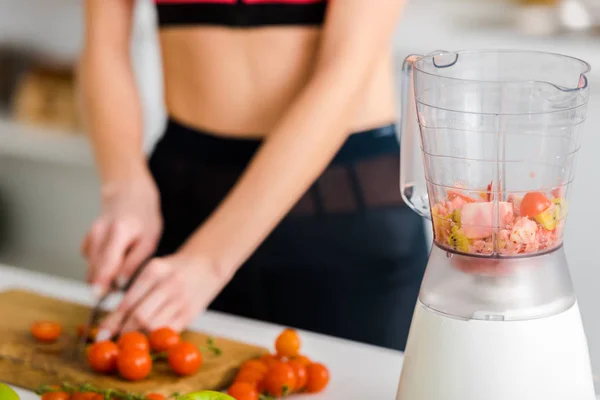 Selektiver Fokus des Mixers in der Nähe einer Frau, die Kirschtomaten schneidet — Stockfoto