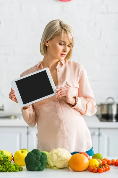 Mujer embarazada rubia sosteniendo tableta digital con pantalla en blanco en la cocina - foto de stock